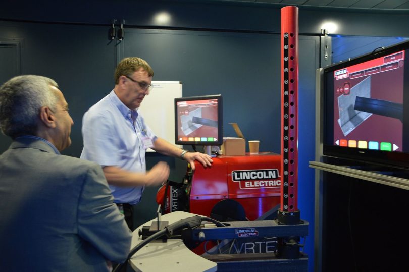 A modern smart factory floor with sensor-equipped machinery and digital monitoring screens.