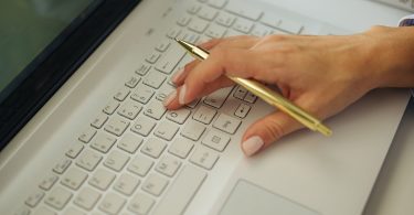 A blogger's workspace with a laptop, notebook and tools laid out