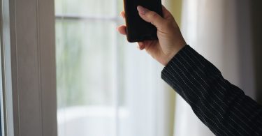 Close-up of a hand holding a smartphone by a window